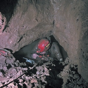 A British cave diver preparing to dive in a tight, muddy sump